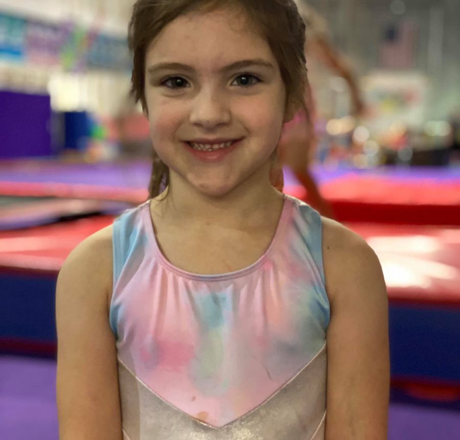 Girl wearing a leotard inside a gymnastics gym.