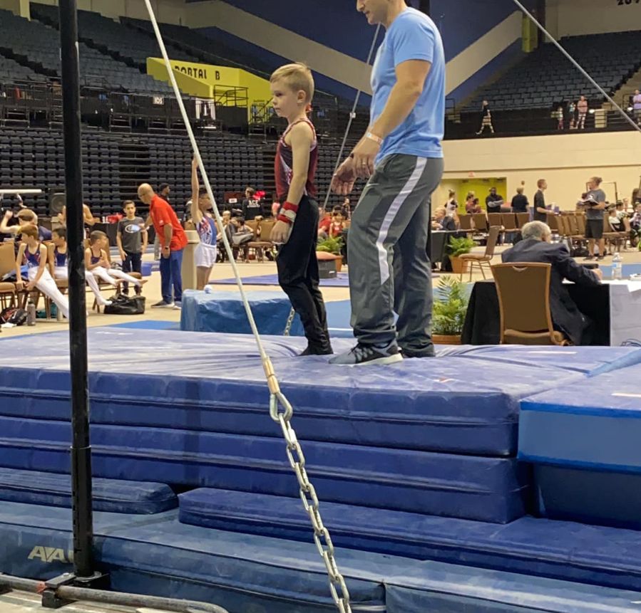 Boy and coach stand on top of padded mats at the Daytona Beach Open.